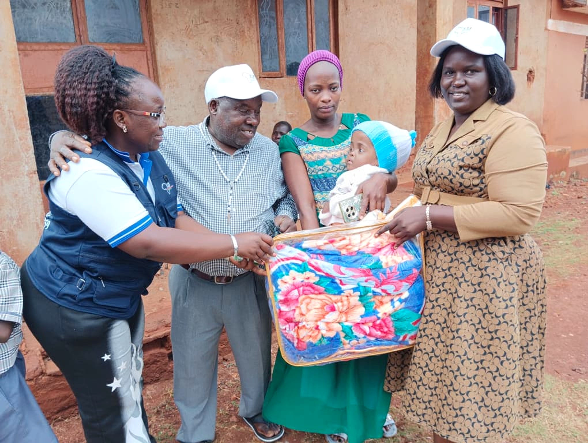 St. Jude Africa team sharing a blanket with a caregiver and child at the Bugembe office