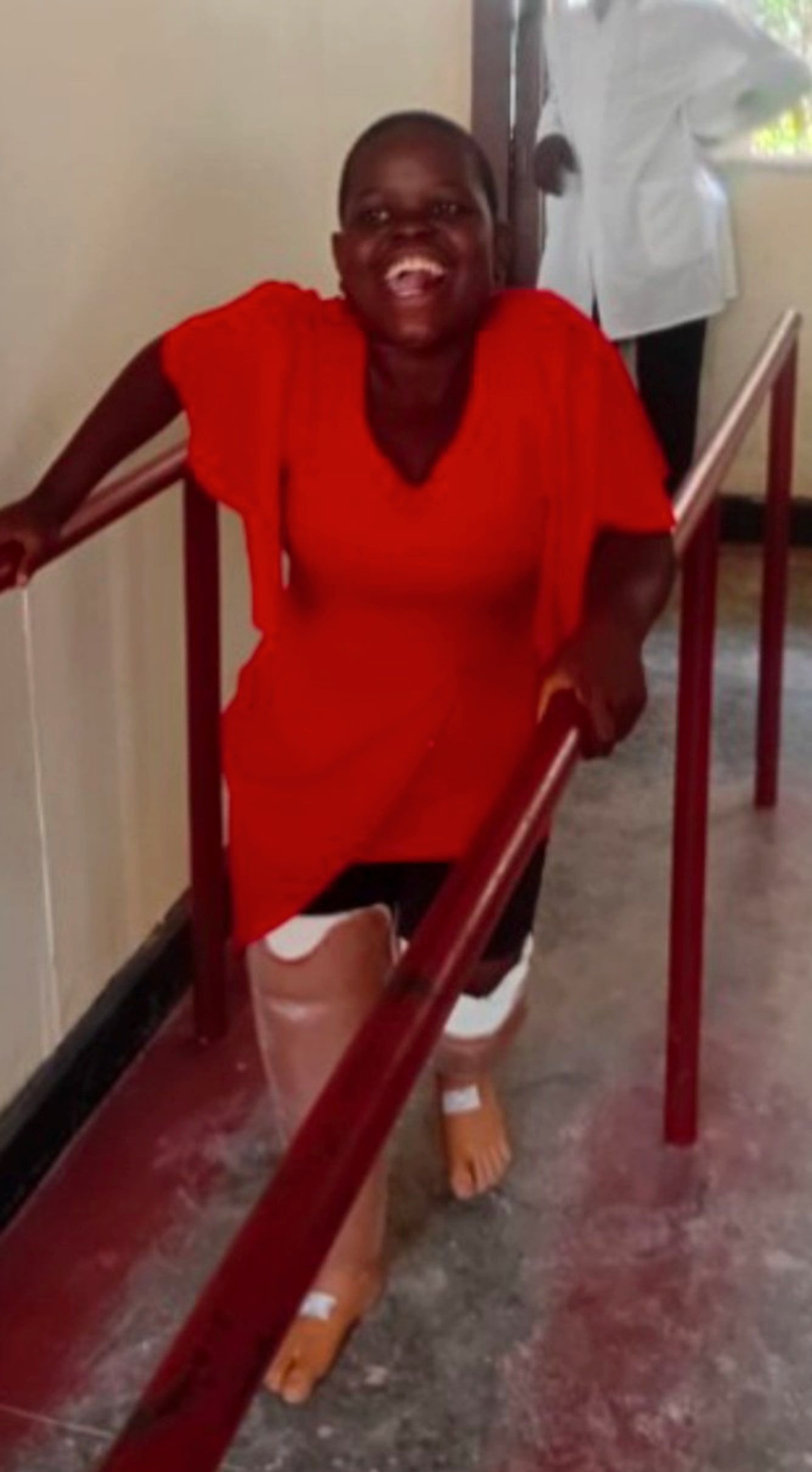 Mariam practising with her prosthetic legs between parallel bars